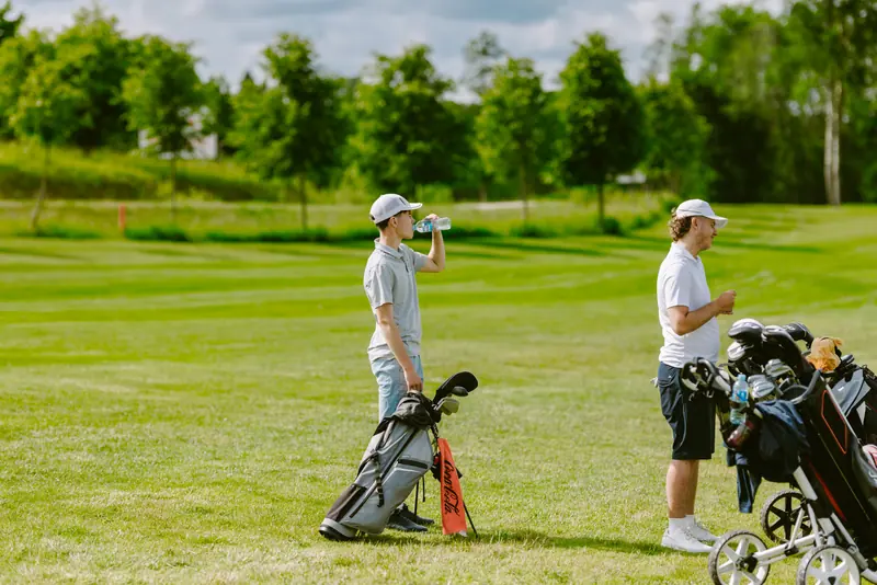 Two golfers with their trolleys on a green course
