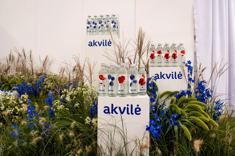 Floral Akvilė glass bottles displayed among meadow flowers at ArtVilnius