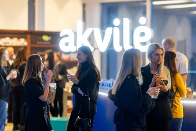 Guests gathered around an illuminated Akvilė display at an evening event