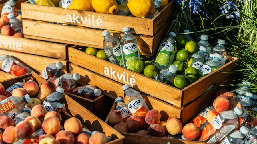 Akvilė Bubbles displayed among fresh citrus and peaches in wooden crates