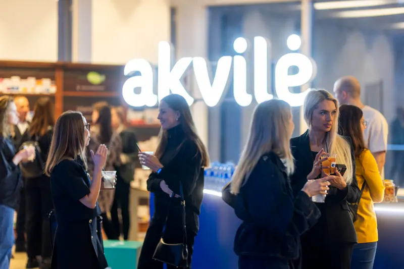 Guests gathered around an illuminated Akvilė display at an evening event