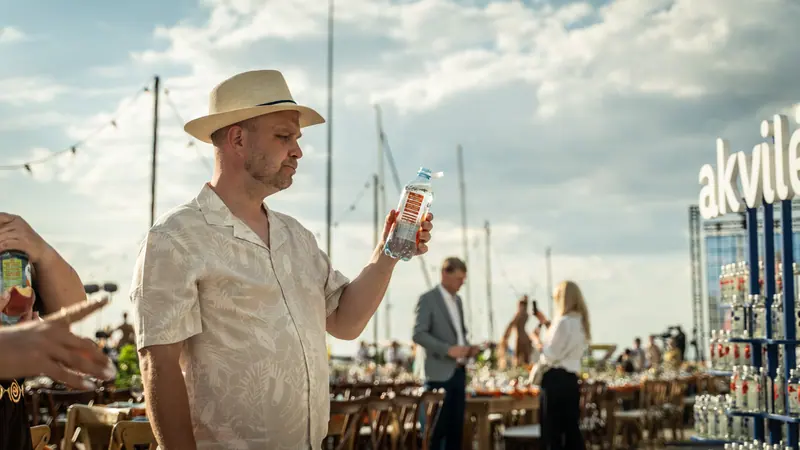 A guest raising a glass beside the Akvilė outdoor refreshment display