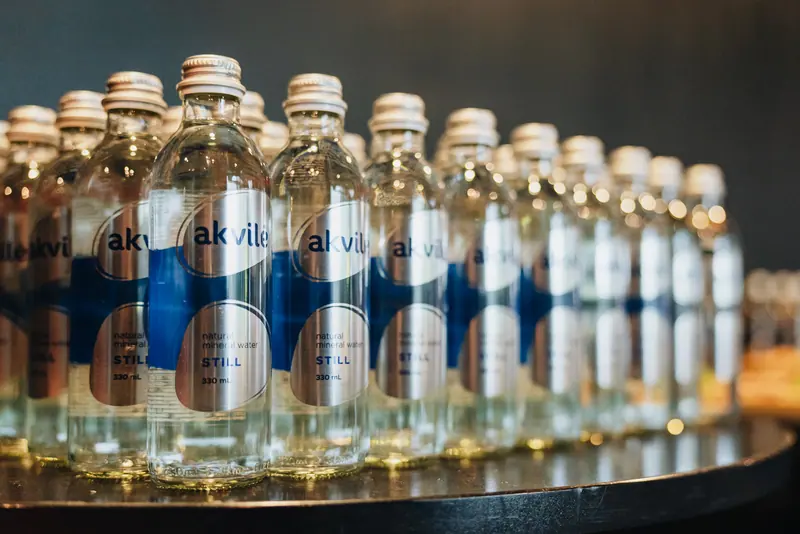 Rows of floral Akvilė glass bottles prepared for an indoor reception