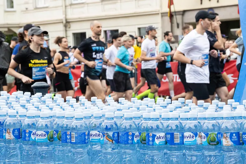 Runners passing a long table of Akvilė water at a race refreshment station