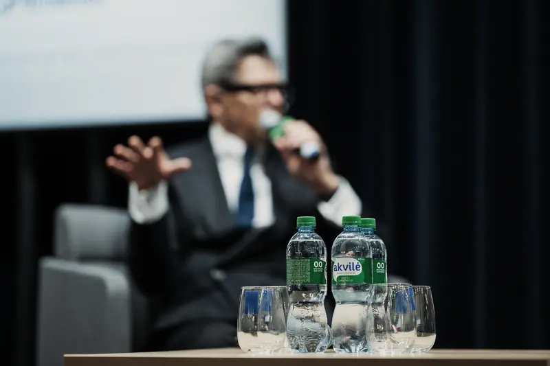 A speaker at a panel discussion with Akvilė water on the table